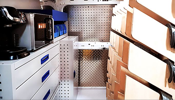 Laderaum mit Hufeisenregal, Kaffeemaschine, Mikrowelle und ausreichend Stauraum für Werkzeug und Kleinteile.